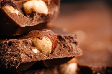 Fındıklı sütlü çikolata parçaları, zengin doku ve kremalı kaplama, gıda tasarımı ve reklamcılığı için kaliteli şekerleme arka planı.