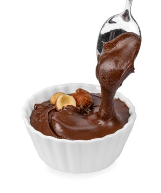 Yumuşak çikolata fındık, kaşıktan beyaz kaseye damlıyor. Parlak desen, ambalaj ve yemek tasarımı için temiz bir zemin üzerine izole edilmiş..