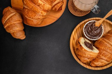 Çikolatalı kruvasan ve koyu arkaplanda kahve, reklam için fırın kahvaltısı konsepti, afişler, menüler ve kafe markası..