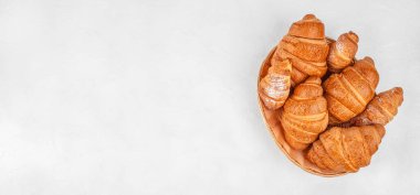 Beyaz arka planda yuvarlak sepetli çeşitli altın kruvasanlar, geniş kopya alanı olan üst görünüm fırın kompozisyonu.