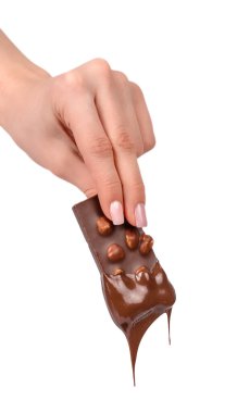Parlak erimiş çikolataya batırılmış fındıklı çikolata tutan kadın. Hafif arka planda en az tatlı konsepti.