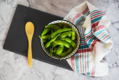 Tahta kaşıkla bir kasede taze edamame kapsülleri. Doğal yeşil soya fasulyesi.