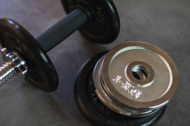 Beton bir yüzeyde farklı ağırlık ve boyutlarda istiflenmiş demir levhalarla aptallar.