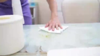 Bir kadın kozmetoloji ofisinde yüzeyleri dezenfekte eder.