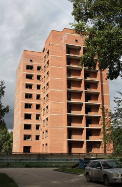 Çok katlı bina yapım aşamasında. Gökyüzüne karşı bulutlu pencereler var.