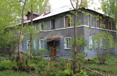 Yazın köy bahçesinde bahçeli eski gri bir apartman dairesi.