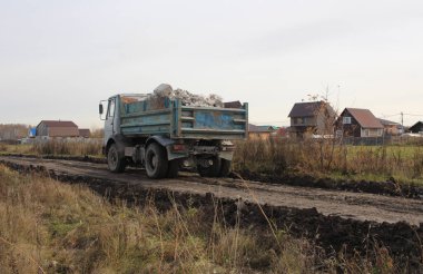 yüklenmiş çöp kamyonu köy otomobili inşaatında yola çıkıyor.