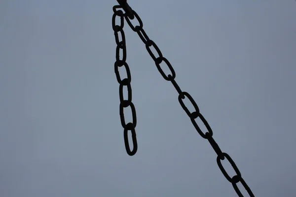 metal chain of iron links hanging on a grey background dark