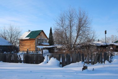 Tahta bir çit köyde kışın bitmemiş bir evi kapatıyor.