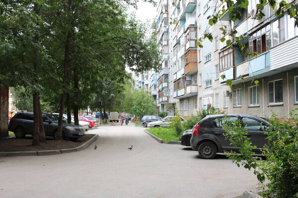 Russia, Novosibirsk 15.08.2020: courtyard with driveway near a multi-storey building parked cars
