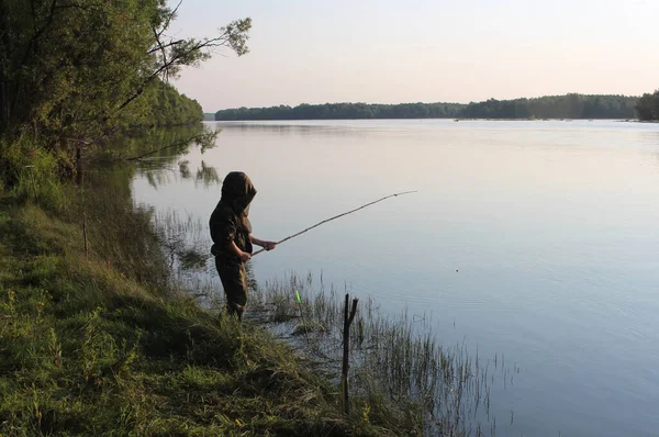 ロシア ノヴォシビルスク05 2020 釣竿を持つ少年が夏に川岸で魚を捕まえる ロイヤリティフリーのストック写真