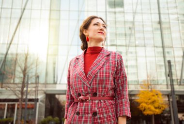 Dışarıda başarılı bir ofis çalışanı. Kırmızı elbiseli gülümseyen kadın iş toplantısına gidiyor.