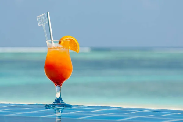 Orange Tropical Cocktails near the Swimming Pool on Background of Warm turquoise ocean. Exotic Summer Vacation.