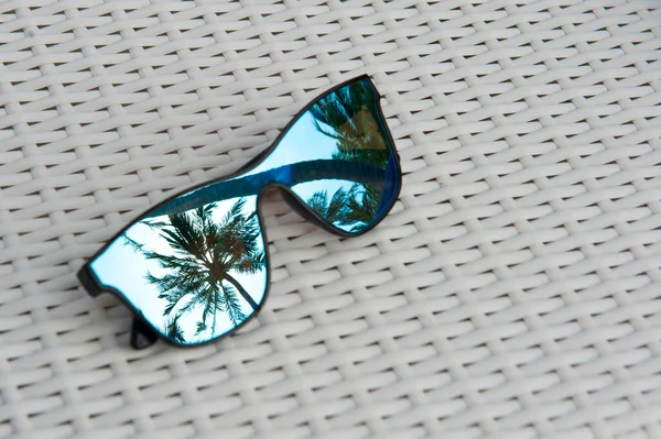 Niebieskie Okulary Białym Stole Rattanem Odbicie Palm — Zdjęcie stockowe