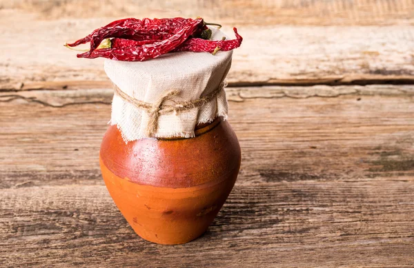 Jarro velho e pimenta vermelha seca na mesa de madeira — Fotografia de Stock