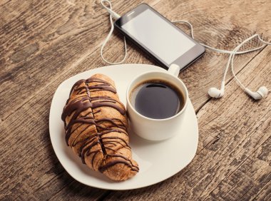 kahve ve kruvasan ile akıllı telefon ve kulaklık