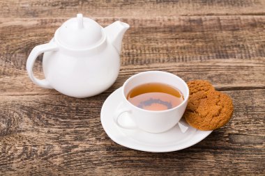 Fildişi çay bardağı tatlı kurabiye ve ahşap palet üzerinde su ısıtıcısı ile