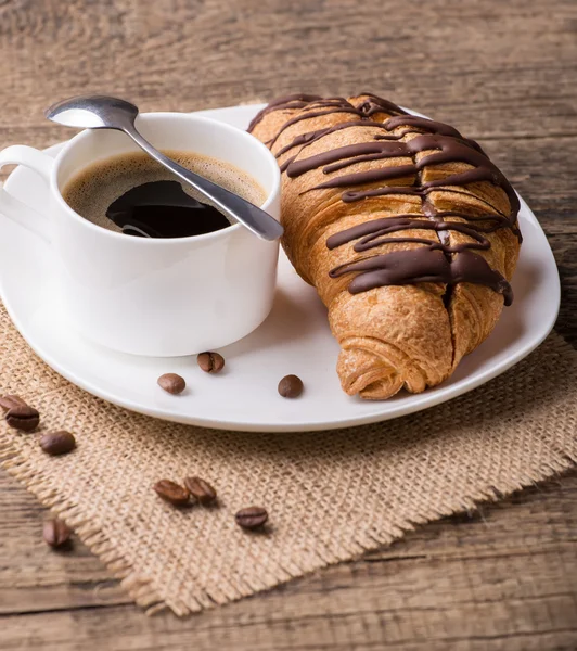 Kahvaltınız, kahveniz ve kruvasanlarınızla ahşap masada.