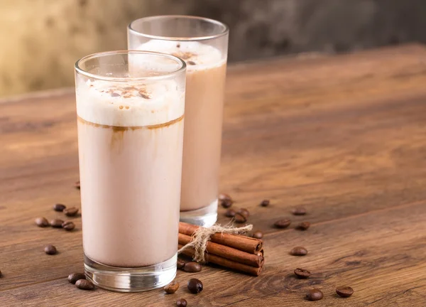 Fulla glas mjölk cocktail och kaffebönor på trä backg — Stockfoto