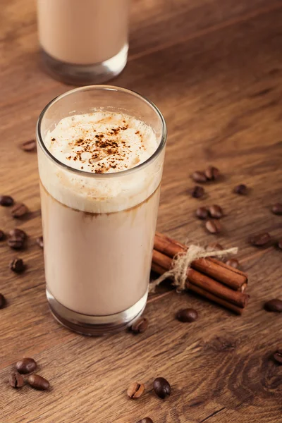 Vaso lleno de cóctel de leche y granos de café en el respaldo de madera — Foto de Stock