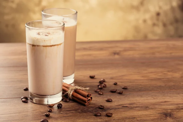 Tam bir bardak süt kokteyl ve kahve çekirdekleri ahşap backg üzerinde