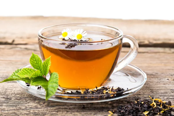 Szkła kubek herbaty kwiat rumianku i liści mięty, na drewnianym tarasem brązowy — Zdjęcie stockowe