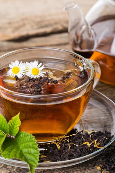 Glas kop thee met kamille bloem en muntblad, op bruin woode — Stockfoto