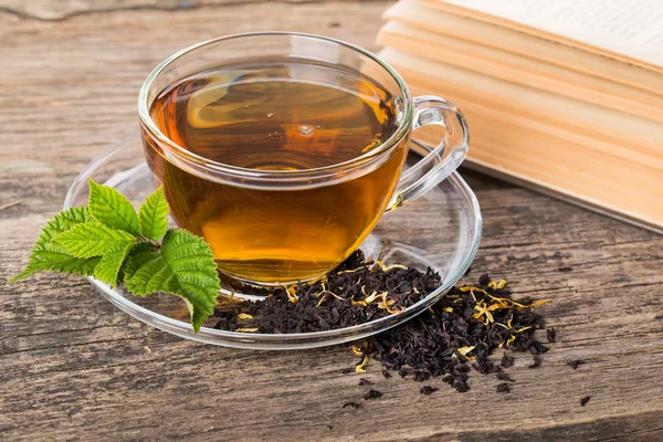 Skleněný šálek čaje s a lístkem máty, hnědé dřevěné paletě — Stock fotografie