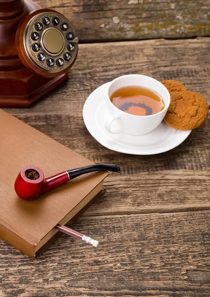 Tasse de thé ivoire avec biscuit sucré, pipe à tabac vieux téléphone et — Photo