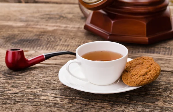 Taza de té de marfil con galletas dulces, teléfono viejo y pipa de tabaco — Foto de Stock