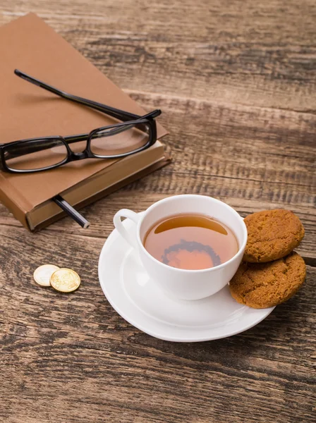 Imagen de taza de té de marfil con galletas dulces, vasos y dinero en w — Foto de Stock