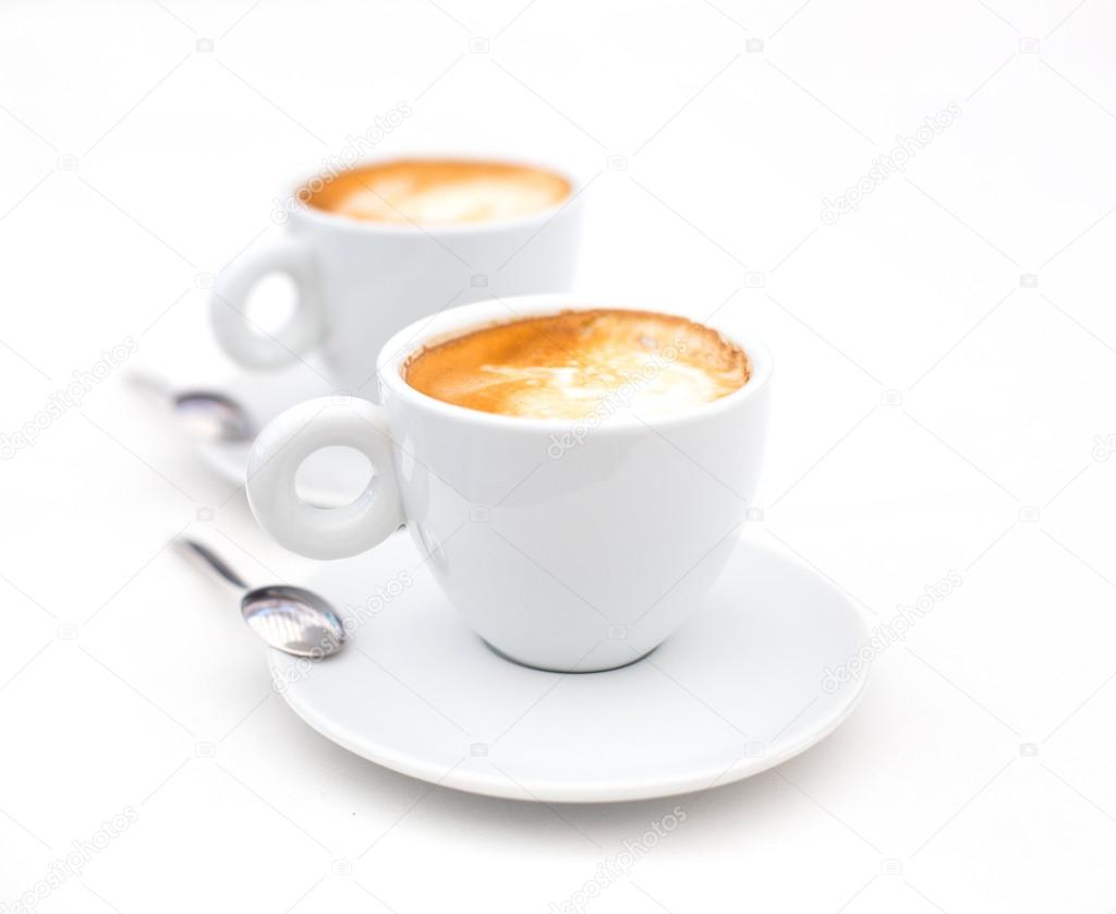 Two white cups of Cappuccino coffee with heart shaped milk foam