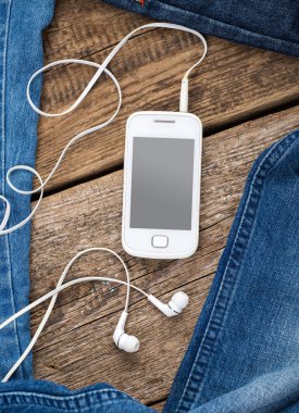 Kot eski ahşap arka kulaklık ile hareket eden smartphone çevresinde