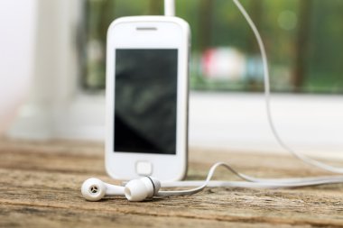 Kulaklık ve eski ahşap izole ekranda beyaz akıllı telefon