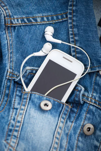 Kopfhörer und Smartphone in der Hosentasche alte Jeansjacke — Stockfoto