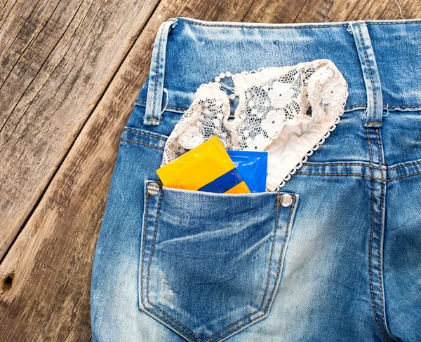 En ung man i jeans med en kvinnas trosor och kondomer i hans Persson — Stockfoto