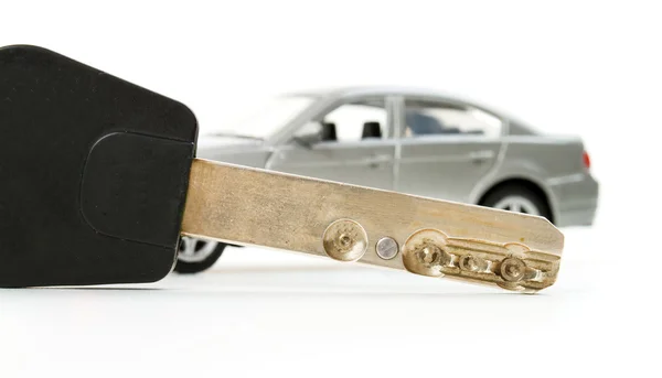 Chave e pequeno carro de brinquedo em borrão isolado no fundo branco — Fotografia de Stock