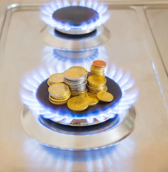 Chamas azuis de gás natural queimando de um fogão a gás com moedas de euro — Fotografia de Stock