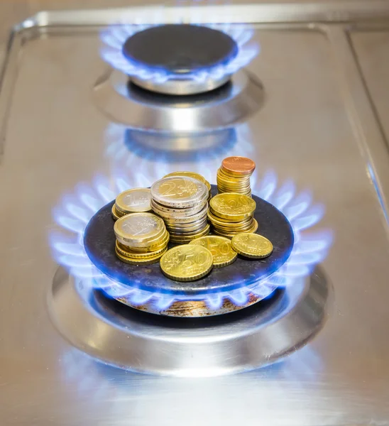 Chamas azuis de gás natural queimando de um fogão a gás com moedas de euro — Fotografia de Stock