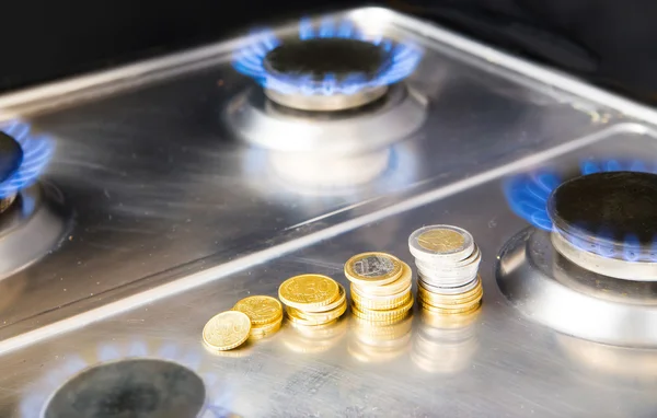 Chamas azuis de gás natural queimando de um fogão a gás com moedas de euro — Fotografia de Stock