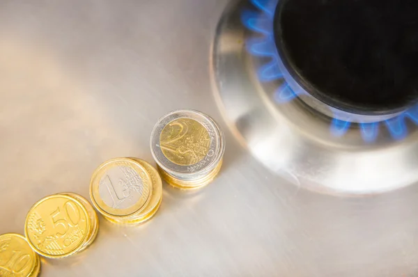 Chamas azuis de gás natural queimando de um fogão a gás com moedas de euro — Fotografia de Stock