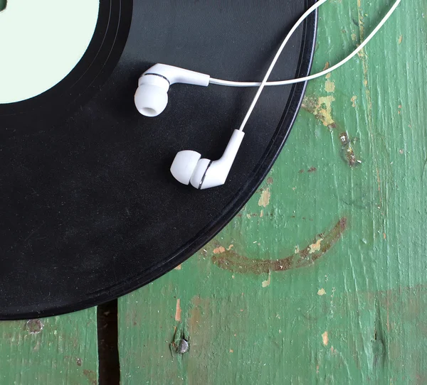 Черный виниловый диск с наушниками на старом зеленом деревянном столе — стоковое фото