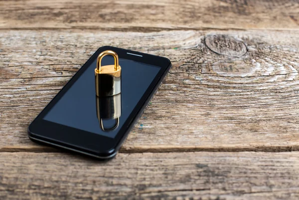 Mobiele telefoon en vergrendelen op houten bureau — Stockfoto