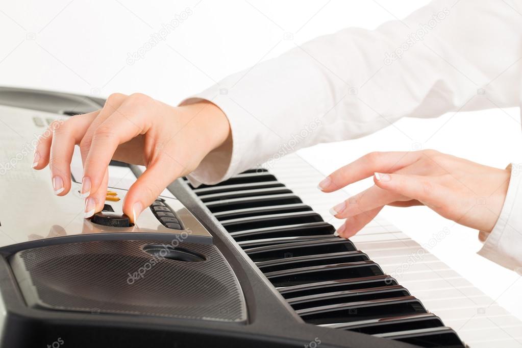 young hands of woman playing synthesizer isolated on white