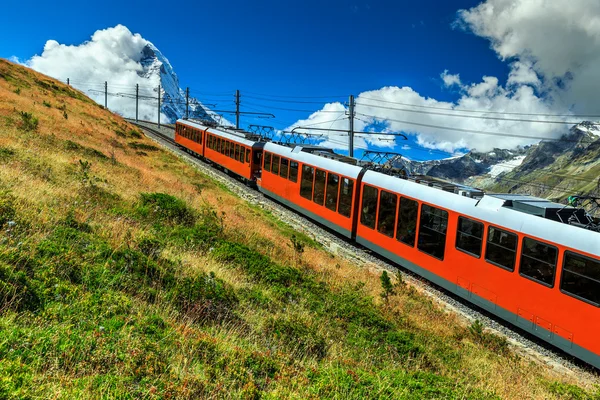 Comboio turístico elétrico e famoso pico de Matterhorn nebuloso, Suíça, Europa — Fotografia de Stock