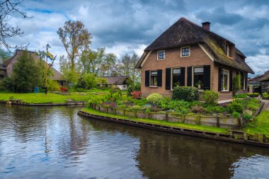 Takdire şayan rıhtım evi ve renkli çiçeklerle büyüleyici küçük süs bahçesi, Giethoorn, Hollanda, Avrupa