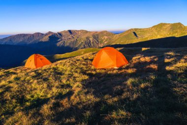 Dağ sırtında renkli çadırları olan bir kamp alanı. Gün doğumunda dağlarda vahşi kamp alanı, Fagaras dağları, Karpatlar, Romanya ve Avrupa