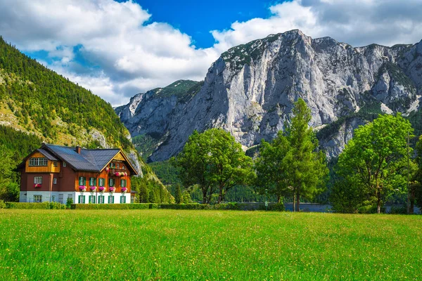 緑のフィールドと背景に高い崖とかわいい高山の木造住宅 アルトゥーゼ湖 オーストリア ヨーロッパ — ストック写真