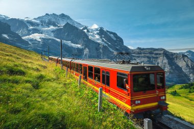 Yokuşta modern çarkıfelek kırmızı turist treni olan bir dağ demiryolu. En ünlü demiryollarından biri, Jungfraujoch, Kleine Scheidegg, Grindelwald, Bernese Oberland, İsviçre, Avrupa