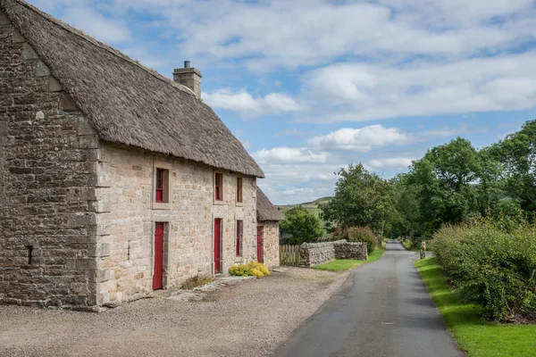 Cottage di pietra inglese con un tetto di paglia Immagine Stock